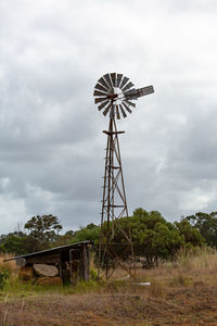 Low angle view of windmill on field against sky