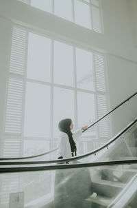 Side view of woman looking through window