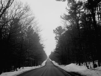 Road amidst snow covered trees against sky