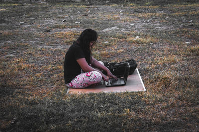 Side view of woman sitting on field