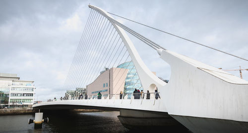 Bridge over river in city against cloudy sky