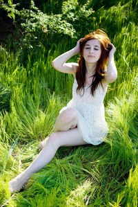 Young woman wearing sunglasses sitting on field