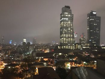 Illuminated buildings in city against sky at night