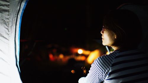 Portrait of woman sitting on illuminated car at night