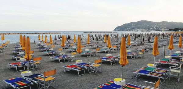 Chairs on beach by sea against sky