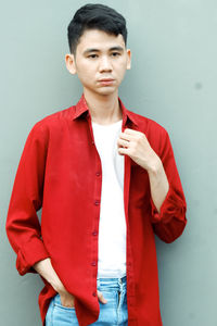 Portrait of young woman using mobile phone while standing against wall