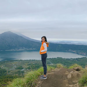 Full length of woman standing on mountain against sky