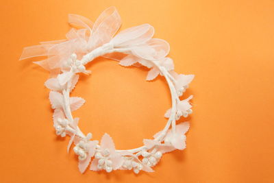 Directly above shot of white wreath on orange background