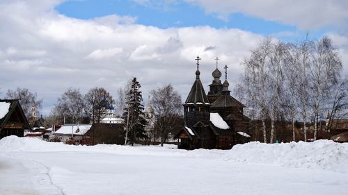 Snow covered trees and buildings against sky