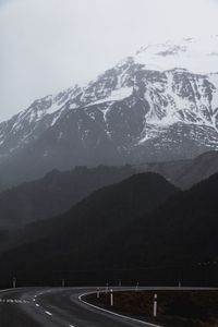 Road leading towards snowcapped mountains against sky