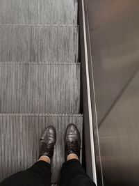 Low section of man standing on escalator
