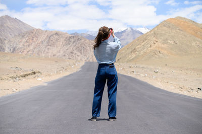 Man standing on road against mountain range