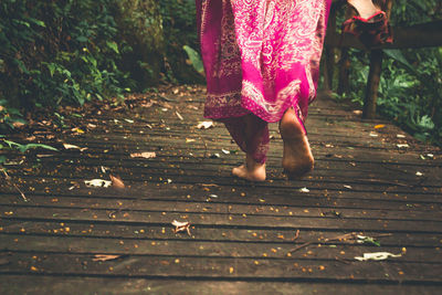 Low section of woman walking on boardwalk