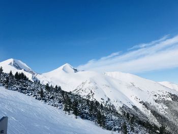 Scenic view of snowcapped mountains against blue sky