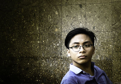 Portrait of young man standing against wall