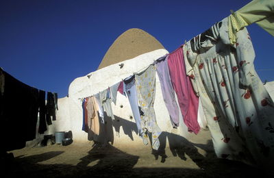 Low angle view of cloths hanging on rope against clear blue sky