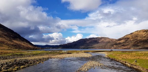 Scenic view of lake by mountains against sky
