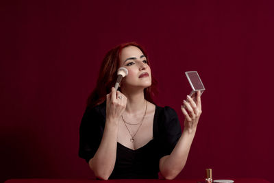 Young woman using mobile phone while sitting on table