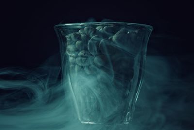 Close-up of coffee beans in glass container against black background