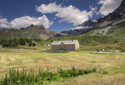 Houses on field by mountains against sky