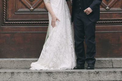 Low section of wedding couple standing outdoors