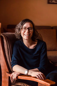 Portrait of smiling young woman sitting on sofa at home