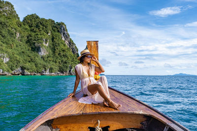 Woman sitting on boat against sea against sky