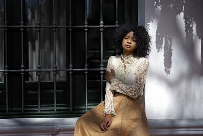 Portrait of young woman standing against wall