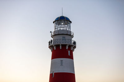 Lighthouse in red and white colors on the seashore, river bank or lake shore. travel and tourism. 