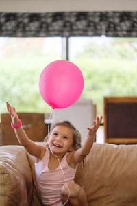 Little girl playing with a pink balloon at home