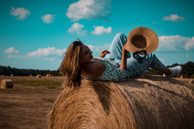 A beautiful young ukrainian woman with hat is lying on a hay bale and smiling