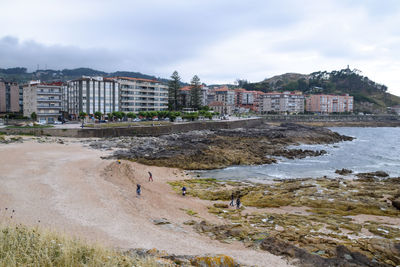 Buildings by sea against sky