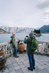 Rear view of man standing by lake