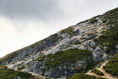 Low angle view of person on rock against sky