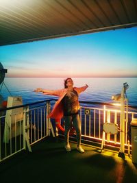 Full length of man standing on railing against sea