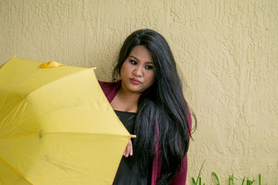 Portrait of young woman holding yellow umbrella