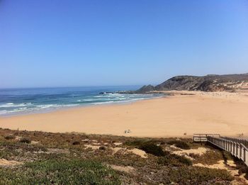 Scenic view of beach against clear blue sky