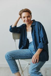 Portrait of young woman sitting against white background