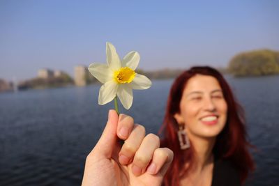 Close-up of smiling woman with red flower in water