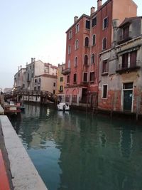 Canal amidst buildings in city against sky