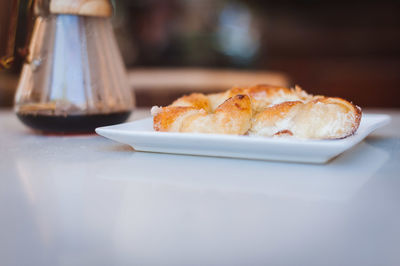 Close-up of coffee filter with croissant on table