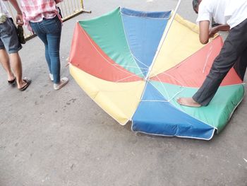 Low section of people standing on multi colored umbrella