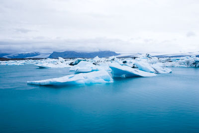 Aerial view of icebergs in sea against sky