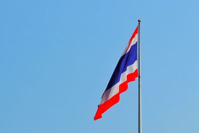 Low angle view of flag against clear blue sky