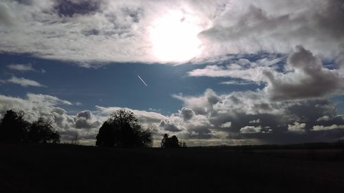 Silhouette of trees against cloudy sky