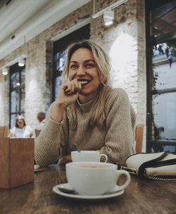 Portrait of a blonde woman smiling at a coffee.