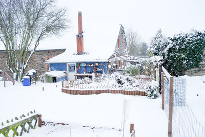 Traditional building on snow covered field against sky