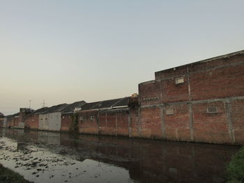 Old building by river against clear sky