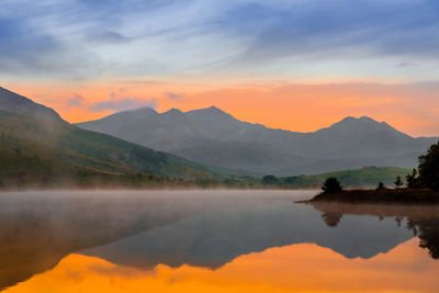 Scenic view of lake and mountains against sky during sunset