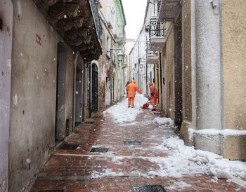 People cleaning snow in alley during winter